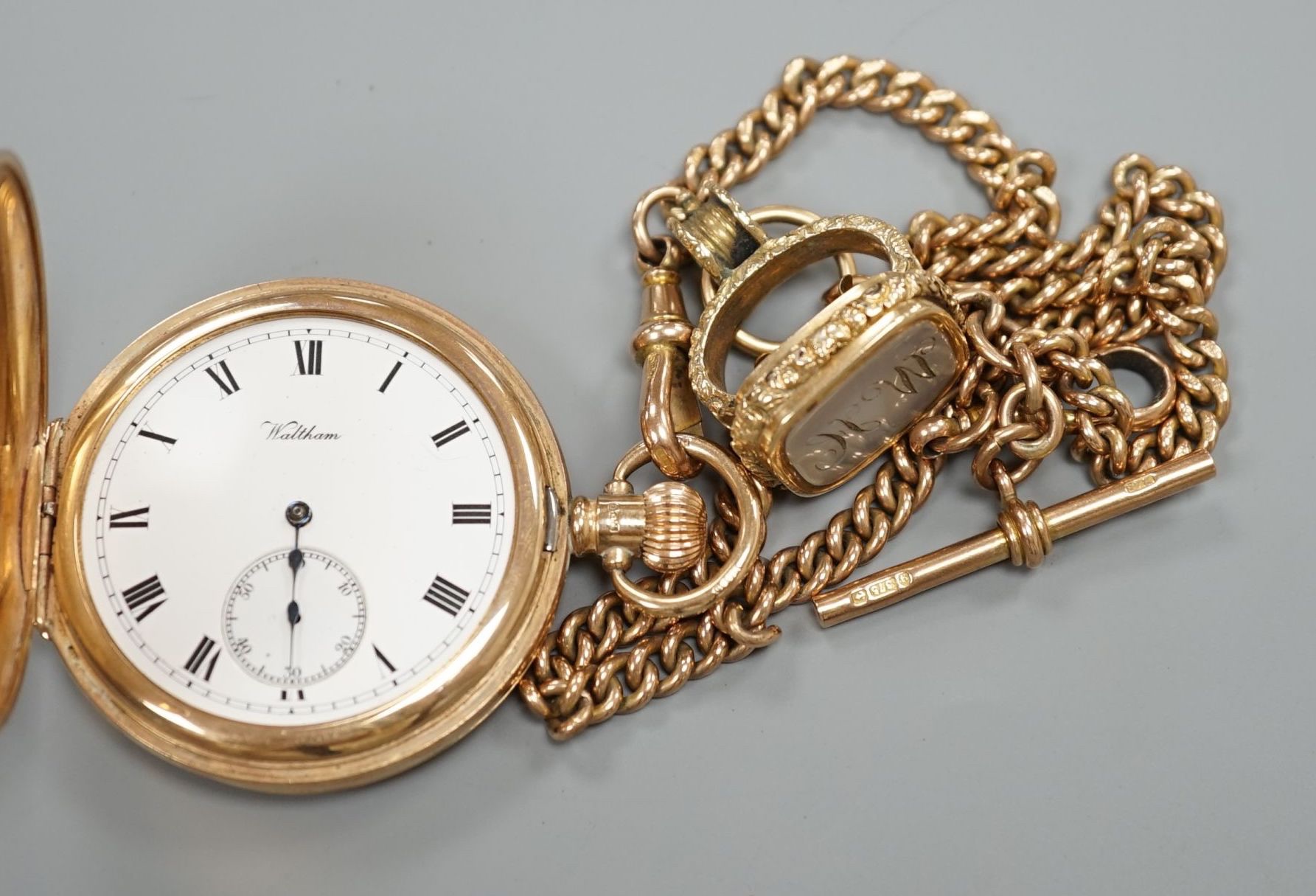 A 1920's 9ct gold Waltham keyless half hunter pocket watch, on a 9ct gold albert, hung with a Victorian yellow metal overlaid and carnelian set fob seal